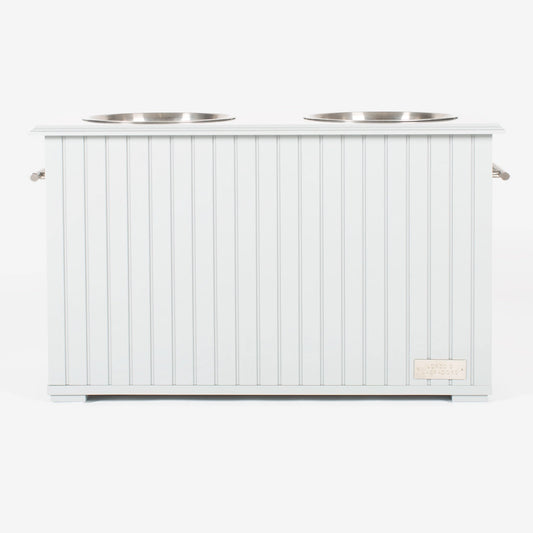 Station alimentaire blanche avec deux bols en acier inoxydable, conçue pour stocker et servir la nourriture et l’eau de manière hygiénique.