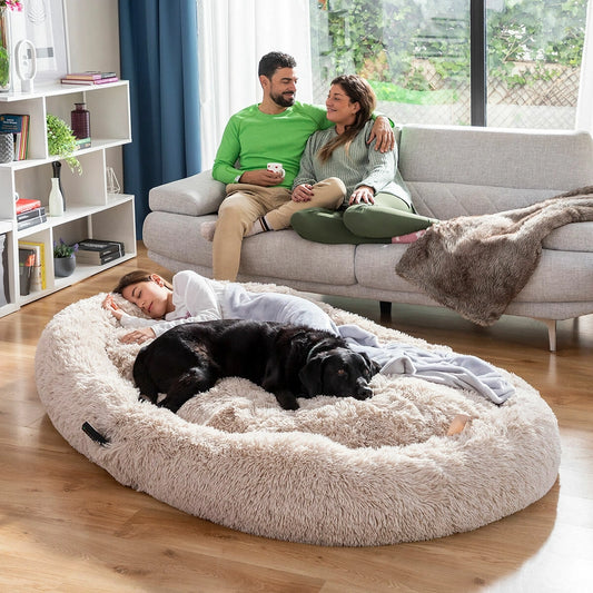 Grand panier douillet imitation fourrure beige pour chien, lit XXL ultra moelleux et anti-stress, parfait pour les grands chiens recherchant confort et sécurité dans le salon.