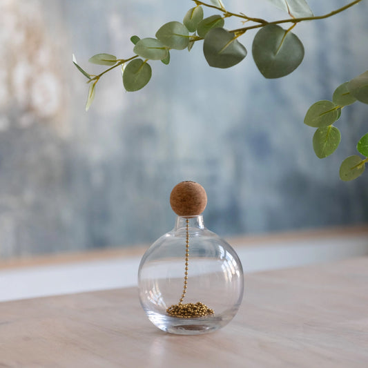 Le jouet interactif The Tail pour chats, accompagné d'un vase en verre contenant des perles dorées. Émet un tic-tac engageant lorsqu'il est retiré, captivant immédiatement l'attention des félins.
