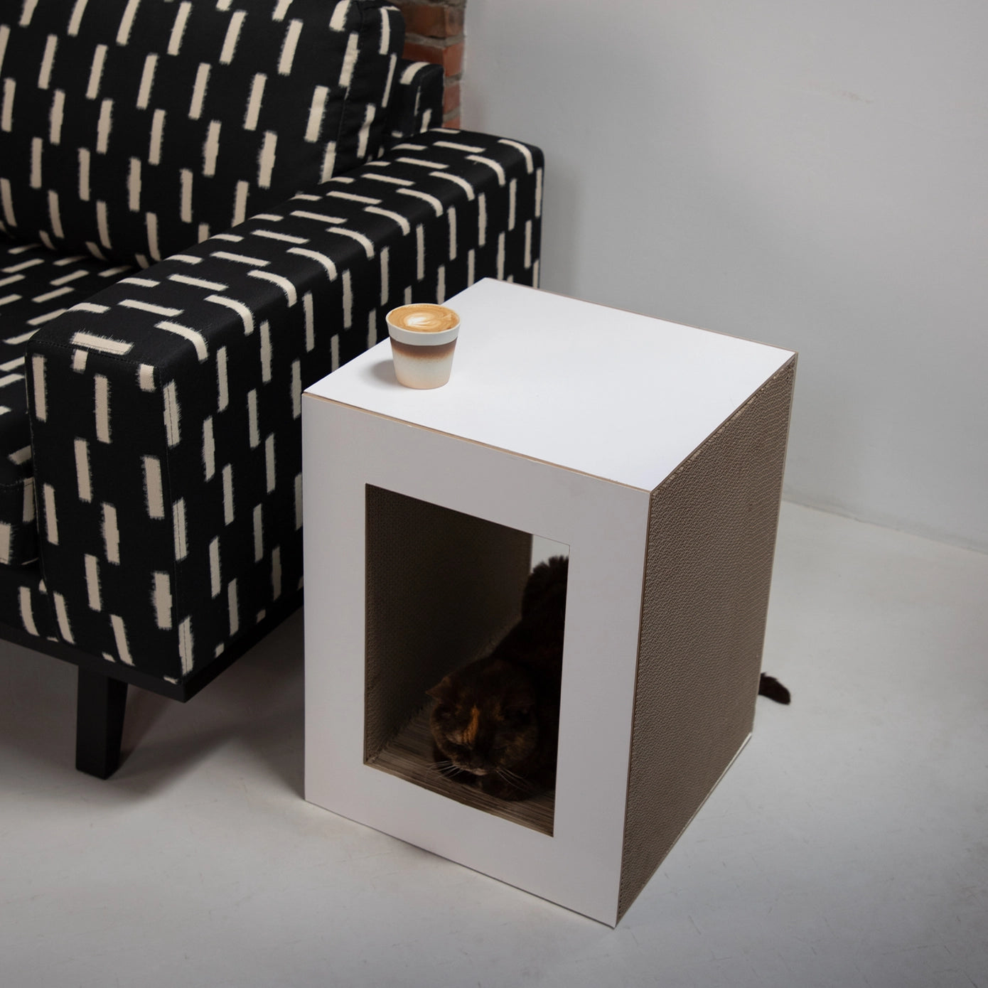 image d'une table griffoire pour chat multifonctionnelle en carton renforcé gris et blanc , offrant une cachette et une surface griffoir durable.